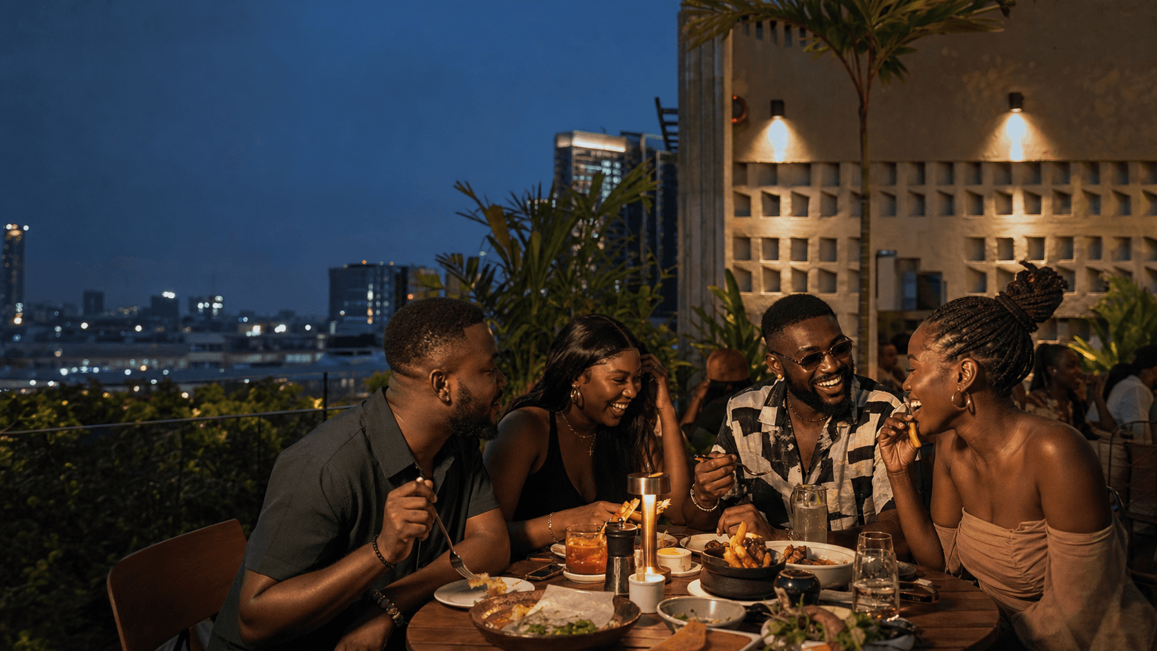Four friends sharing food and laughing at a rooftop restaurant in Lagos